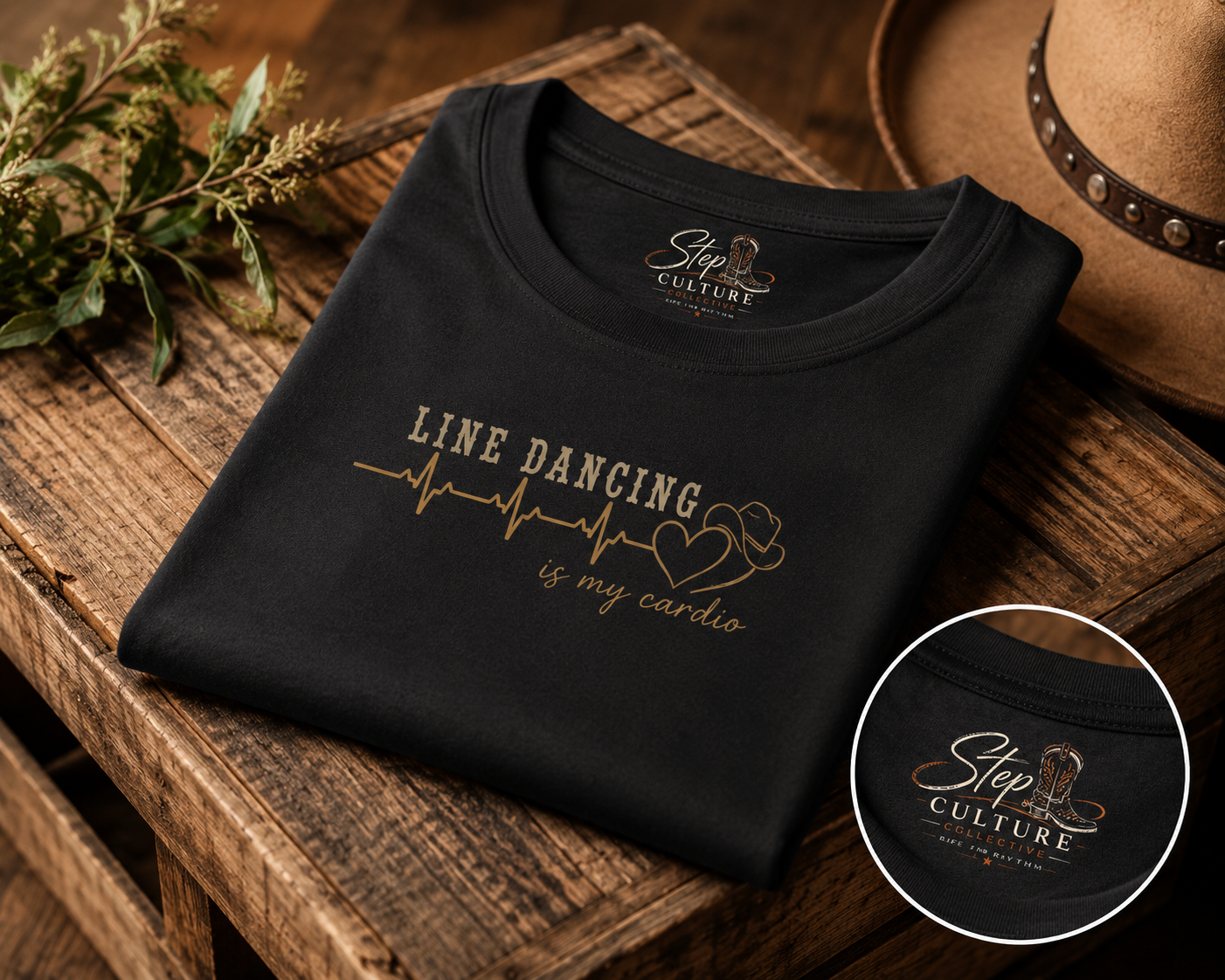 Black t-shirt with 'Line dancing is my cardio' design on a wooden surface with a hat and plant.